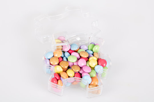 Round multi-colored sweets in plastic puzzle box on a white background