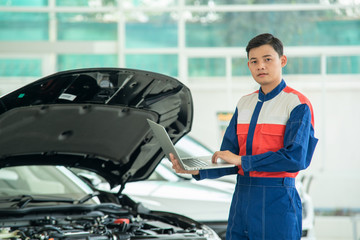 Mechanic perform vehicle checkup and use notebook computers to record engine checks,Concept of working in a car service center.