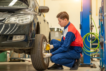 Car mechanic changing tire in professional car repair,Car Maintenance in the Professional Service.