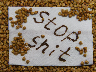 Inscription STOP SHIT with background of uncooked buckwheat seeds. Stay strong in Coronavirus dangerous environment. Food supplies concept.