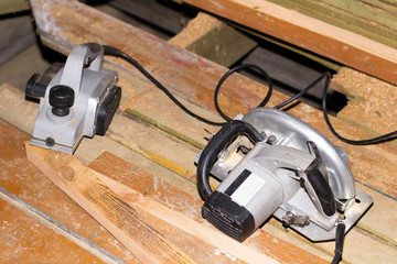 construction site, on the floor on the boards there is an electric planer and an electric saw.