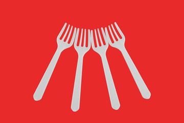 four plastic white forks on a red background. isolate. Top view.