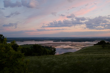 Obraz premium The concept of tourism and solitude with nature. Beautiful pink sunrise on a plain overlooking the river. 