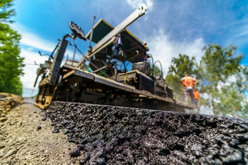Obraz premium Tandem vibration roller compactor working on asphalt pavement, selective focus on road repair.