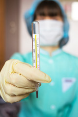 Thermometer in the hand of a female doctor physician. Temperature measurement with a thermometer. Fever measurement.