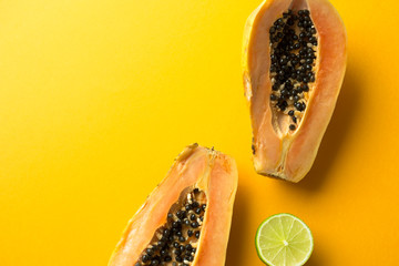 Summer composition. Tropical lime and papaya fruits cut in half lie on a yellow background. Summer...