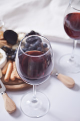 Two glass of red wine and plate with assorted cheese, fruit and other snacks for party