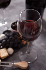 Two glass of red wine and plate with assorted cheese, fruit and other snacks for party