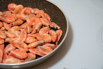 small cocktail shrimps are fried in a pan. 