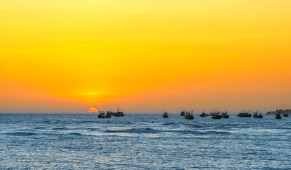 Sea landscape at sunset when the sun shines down the horizon shines bright yellow, beneath the fishing boats anchored peacefully