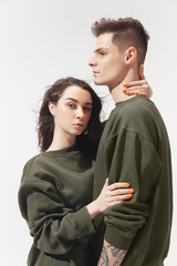 Supporting. Trendy fashionable couple isolated on white studio background. Caucasian woman and man posing in basic minimal unisex clothes. Concept of relations, fashion, beauty, love. Inclusive.