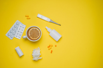 Pills, medical thermometer, nose spray and lemon. Different medications on yellow background. Cold and flu home remedies. Disease self-treatment concept. Flat lay. Top view with blank space for text. 