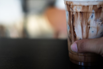 Delicious iced mocha in clear plastic glass on wood table