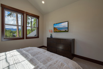 Bright new natural tones bedroom with queen size bed with grey carpet and three windows,