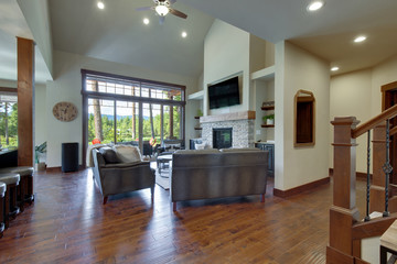 An absolute beautiful luxury living room with huge vaulted  ceiling, fire place, harwood floor, amazing furniture, and lots of windows and doors.