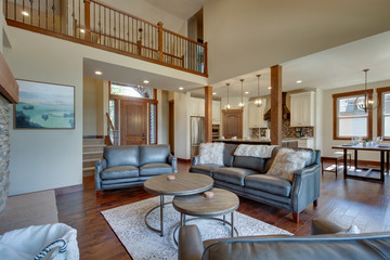 An absolute beautiful luxury living room with huge vaulted  ceiling, fire place, harwood floor, amazing furniture, and lots of windows and doors.