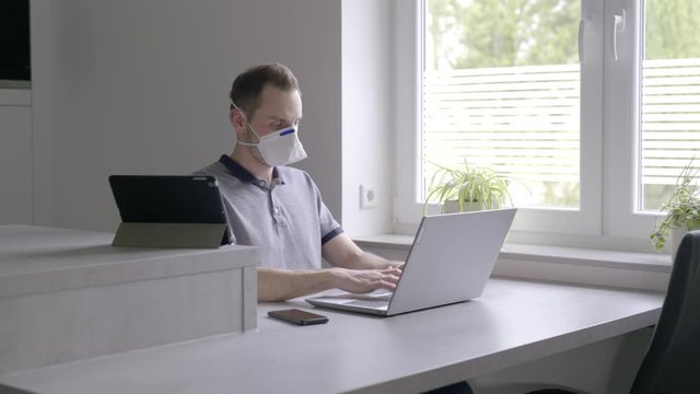 Verzweifelter Mann in quarant&auml;ne arbeitet am Laptop und schaut aus dem Fenster