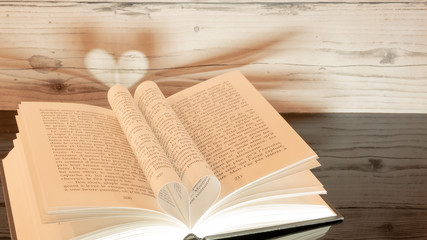  Livre plié en forme de cœur sur fond de bois.