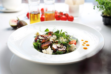 Salad with figs and goat cheese. A plate with an appetizing dish. Application suggestion. Culinary photography, food stylization.