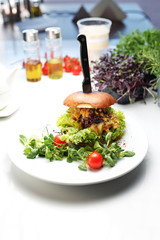 Tasty burger with pulled beef and cheese. A plate with an appetizing dish. Application suggestion. Culinary photography, food stylization.