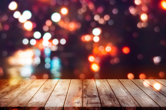 wooden table top with blur scenery of dark night street and colorful neon light bokeh background.