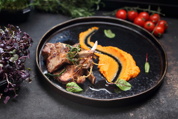Lamb ribs with pumpkin mousse. A plate with an appetizing dish. Application suggestion. Culinary photography, food stylization.