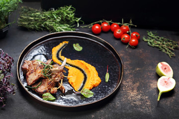 Baked lamb ribs with orange vegetable mousse. A plate with an appetizing dish. Application suggestion. Culinary photography, food stylization.