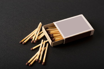 open box of matches, scattered single matches on a black background, macro