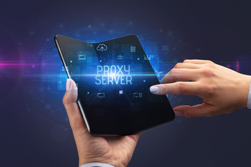 Businessman holding a foldable smartphone with PROXY SERVER inscription, cyber security concept