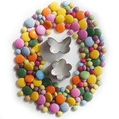 Colorful chocolate candies also called smarties in shape of a Easter egg with decoration isolated on white background. Easter background