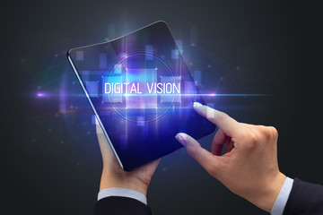 Businessman holding a foldable smartphone with DIGITAL VISION inscription, new technology concept