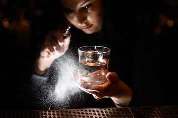 woman holds with one hand glass with drink and spray on it.
