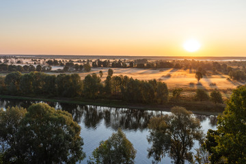 Amazing perfect morning foggy landscape in scenic countryside of Ukraine. Aerial view at horizon line, meadows, green forests and dark long shadows of sunrise sun seen on misty ground.