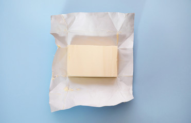 Piece of butter on blue background, top view - obrazy, fototapety, plakaty
