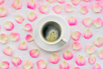 Cup of black coffee and pink rose petals