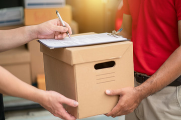 Close up customer hands signing to get package parcel cardboard from delivery man.
