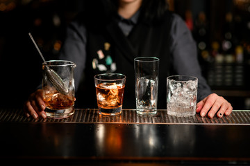 Different glasses with ice and drinks stand at the bar.