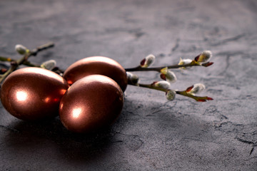 Easter composition with eggs and twigs of willow blossom. minimal background with gold Easter eggs on black background. Copy space.