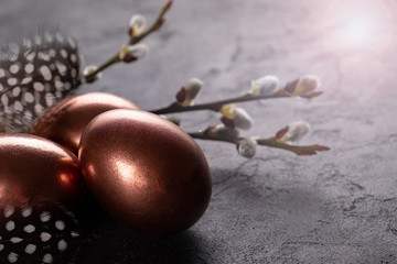 Easter composition with eggs and twigs of willow blossom. minimal background with gold Easter eggs on black background. Copy space.