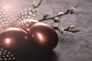 Easter composition with eggs and twigs of willow blossom. minimal background with gold Easter eggs on black background. Copy space.