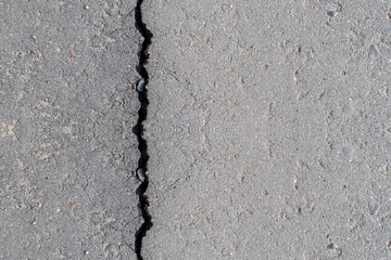 Cracks in the old gray asphalt. Abstract background