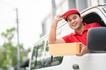 Young delivery man in red uniform driving van,truck to sending parcel cardboard box cargo service concept.