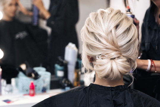hairstyle bun on the head of the girl blonde. Preparation for the wedding day in beauty salon