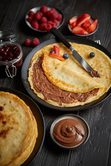 Delicious chocolate homemade pancakes on black ceramic plate