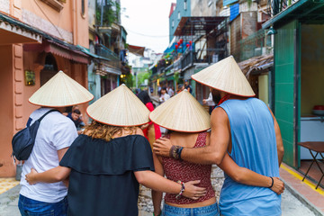 Foreign tourists with Vietnamese conical hats taking photo at narrow train railroad in old town in Hanoi