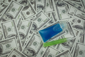 Alcohol gel bottle and money a stack of 100 US dollars banknote a lot of, That was It costs...
