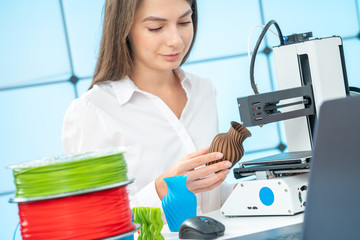 Young female designer works with a 3D printer in a design studio.