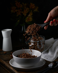 Chocolate granola in white bowl. Dark key photo style. cozy home, homemade breakfast