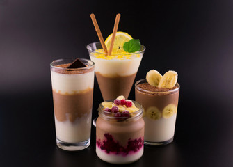  Chocolate-vanilla dessert (pudding) in different glasses on a black background.
