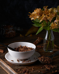Chocolate granola in white bowl. Dark key photo style. cozy home, homemade breakfast